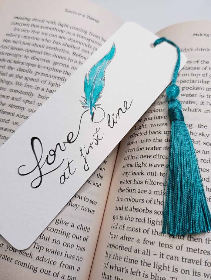 Ručno oslikani označivač stranica (bookmark) s motivom plavog pera i tasselom, dimenzije 15x5, medij akvarel na 300 g/m² papiru. Idealno za ljubitelje knjiga.