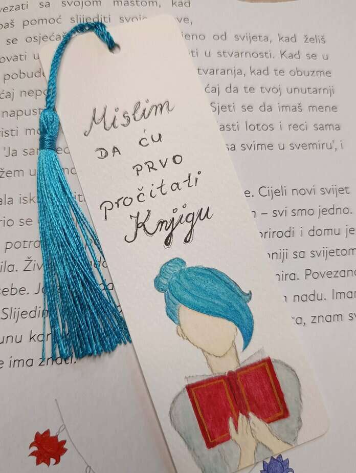 Ručno oslikani označivač stranica (bookmark) s motivom djevojke s plavom kosom kako čita crvenu knjigu i tasselom, dimenzije 15x5, medij akvarel na 300 g/m² papiru. Idealno za ljubitelje knjiga.