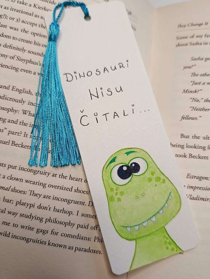 Ručno oslikani označivač stranica (bookmark) s motivom dinosaura T-Rexa i tasselom, dimenzije 15x5, medij akvarel na 300 g/m² papiru. Idealno za ljubitelje knjiga.